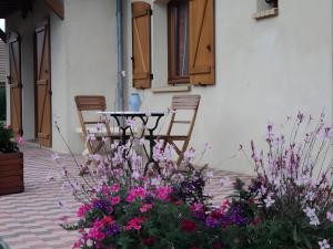 a patio with a table and chairs and flowers at Le Logis Du Mesnil  +3 photos