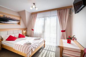 a bedroom with a bed with red pillows and a window at DW Boguń Pokoje i Apartamenty in Białka Tatrzańska