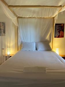a white bed with a canopy and two pillows at Timonier Ecolodge in Mar Lodj