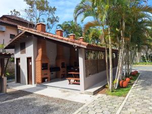 a house with a porch with a table and palm trees at Apartamento em Maresias a 100 metros da praia in Maresias