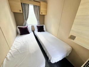 two beds in a small room with a window at california cliffs caravan 2 dunlin in Scratby