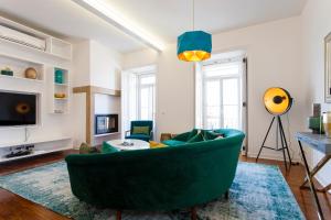 a living room with a green couch and a tv at Bairro Alto Viewpoint Flat in Lisbon