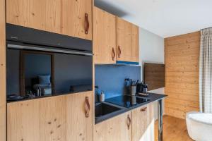 a kitchen with wooden cabinets and a sink at Dent Blanche Resort - TemptingPlaces Collection in Hérémence