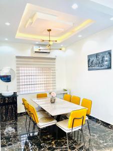 a dining room with a table and yellow chairs at Westtzs Home I in Yaoundé