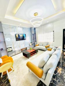 a living room with a white couch and yellow chairs at Westtzs Home I in Yaoundé