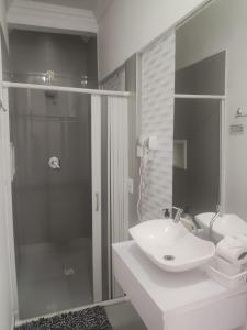 a bathroom with a white sink and a shower at Suits Recanto do Sabiá in Brotas +35 photos