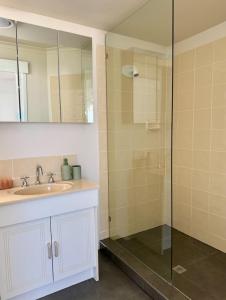 a bathroom with a sink and a glass shower at Margate Beach Studio 4 in Redcliffe