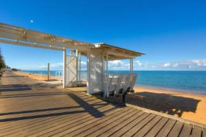 a wooden boardwalk with a bench on the beach at Margate Beach Studio 4 in Redcliffe +23 photos