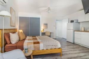 a bedroom with a bed and a couch and a kitchen at Margate Beach studio 2 in Redcliffe