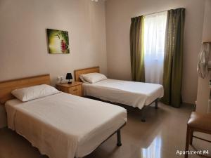 a hotel room with two beds and a window at Riviera Holiday Apartments - Seafront - Wifi in Marsaskala