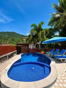a swimming pool with two chairs and an umbrella at SU house Koh Phangan in Thong Nai Pan Yai