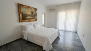 a bedroom with a white bed and a painting on the wall at Kineta Prime Suites No5 in Kineta
