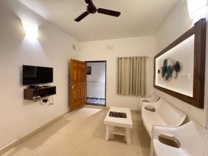 a living room with a couch and a table and a tv at Le Poshe Suite - TIE Hotels in Pondicherry