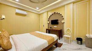 a bedroom with a bed and a desk and a television at Hotel Shree Banke Bihari Heritage in Maheshwar