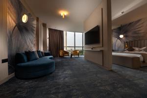 a hotel room with a bed and a blue couch at Hotel Supreme in El Biar