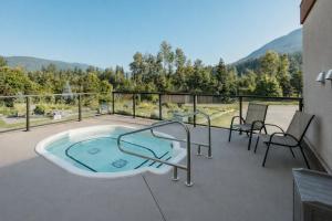 a jacuzzi tub on a balcony with chairs at Northwinds Hotel Revelstoke in Revelstoke