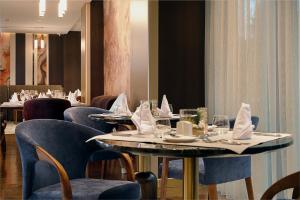 a restaurant with tables and chairs with napkins on them at Hotel Supreme in El Biar +25 photos