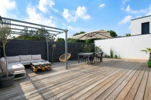 a patio with a couch and a table and an umbrella at Les clos des Aviateurs in Strasbourg