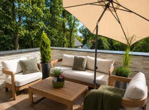 a patio with couches and a table and an umbrella at Waldresidenz Lutz in Bad Lippspringe