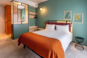 a bedroom with a large bed with an orange blanket at Best Western Plus Hôtel de Robien in Saint-Brieuc