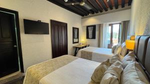 a hotel room with two beds and a flat screen tv at Mision Catedral Morelia in Morelia +39 photos