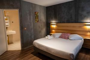 a bedroom with a large bed and a bathroom at Logis - Hotel & Restaurant La Corne d 'Abondance in Bourgthéroulde