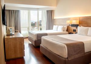 a hotel room with two beds and a large window at Clarion Suites Guatemala City in Guatemala +70 photos