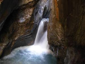 a waterfall in a cave with water rushing through it at Ferienwohnung Rosenlaui in Meiringen