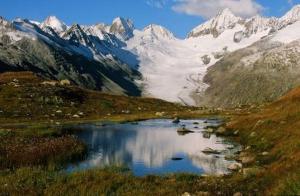 a mountain lake with snow capped mountains in the background at Ferienwohnung Rosenlaui in Meiringen