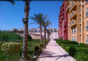 a sidewalk with palm trees next to a building at Cozy chalet in El Alamein