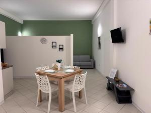 a dining room with a wooden table and white chairs at Scirocco - ideale per coppie e famiglie in Carmiano