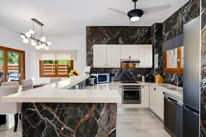 a kitchen with white cabinets and black marble walls at Modern Villa HG08 Pyrinas with Amazing Golf Views, in heart of Aphrodite Hills in Kouklia