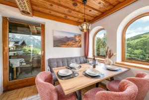 a dining room with a table and chairs and windows at Chalet BergMoment - by myNests in Rohrmoos