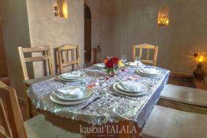 ein Tisch mit Tellern, Gläsern und Blumen darauf in der Unterkunft Alkhayer 2 in Tazzarine