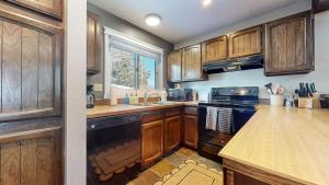 a kitchen with wooden cabinets and a black appliance at Mountain Condo | Spa Pool and Ski Shuttle Access in Mammoth Lakes