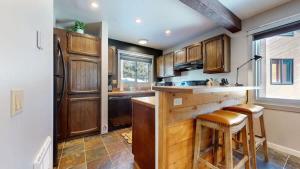 a kitchen with wooden cabinets and a counter with stools at Mountain Condo | Spa Pool and Ski Shuttle Access in Mammoth Lakes +28 photos