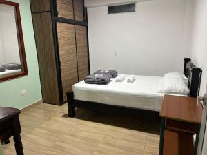 a bedroom with a bed with white sheets and a table at Casa Hotel Villa María - Apia in Apía