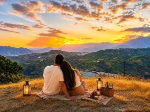 a couple sitting on a blanket watching the sunset at Casa Hotel Villa María - Apia in Apía +3 photos
