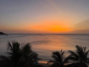 a sunset over the ocean with palm trees on the beach at Oceana Trinco in Trincomalee