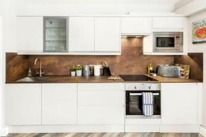 a white kitchen with white cabinets and appliances at Scandi Lux retreat in Stockholm +13 photos