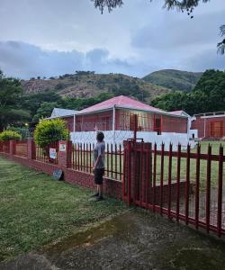 a person standing next to a red fence at JJK free Breakfast in Barberton