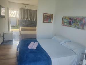a bedroom with two beds with slippers on the bed at Suits Recanto do Sabiá in Brotas