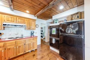 a kitchen with wooden cabinets and a black refrigerator at Dog-friendly, bayfront home w/rocky beach, full kitchen, washer/dryer & firepit in Gouldsboro