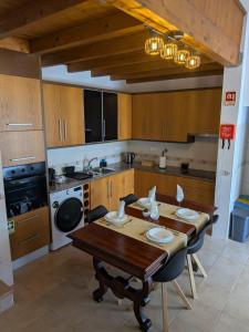 a kitchen with a wooden table with chairs and a sink at Casa Crisel in Aljezur