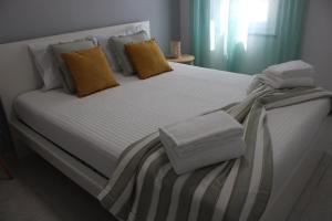 a large white bed with yellow pillows on it at Casa Crisel in Aljezur