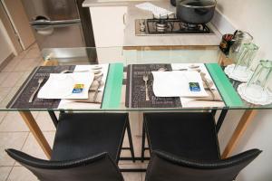a glass table with two chairs and a table with utensils at Direl Lodge in Libreville