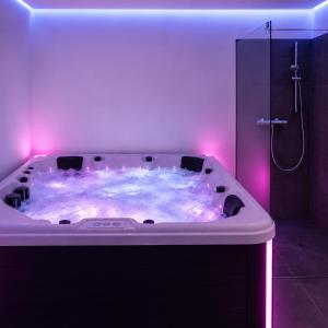 a white bath tub with pink lights in a bathroom at Grafitowe Apartamenty in Czarna Góra +18 photos