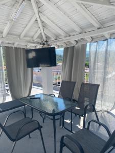 a glass table with chairs and a tv on a patio at Georgia's House Olympiada in Olympiada
