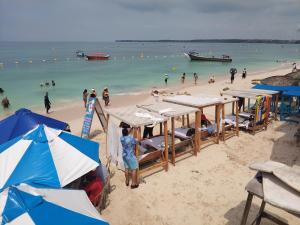a beach with umbrellas and people in the water at Venido del mar beach in Cartagena de Indias