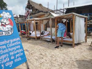 a woman standing next to a sign on the beach at Venido del mar beach in Cartagena de Indias +1 photo